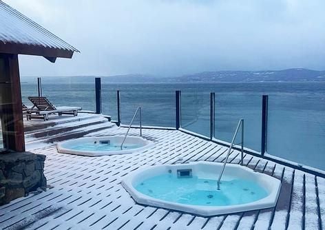 Luxurious waterfront resort nestled in Ushuaia, Argentina, with snow-capped mountains, serene Beagle Channel, and elegant modern architecture at sunset