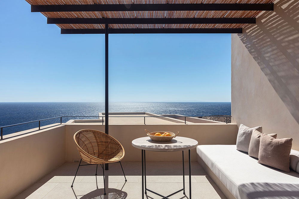 Modern Mediterranean villa with infinity pool overlooking the Aegean Sea, featuring white-washed walls and panoramic sunset views