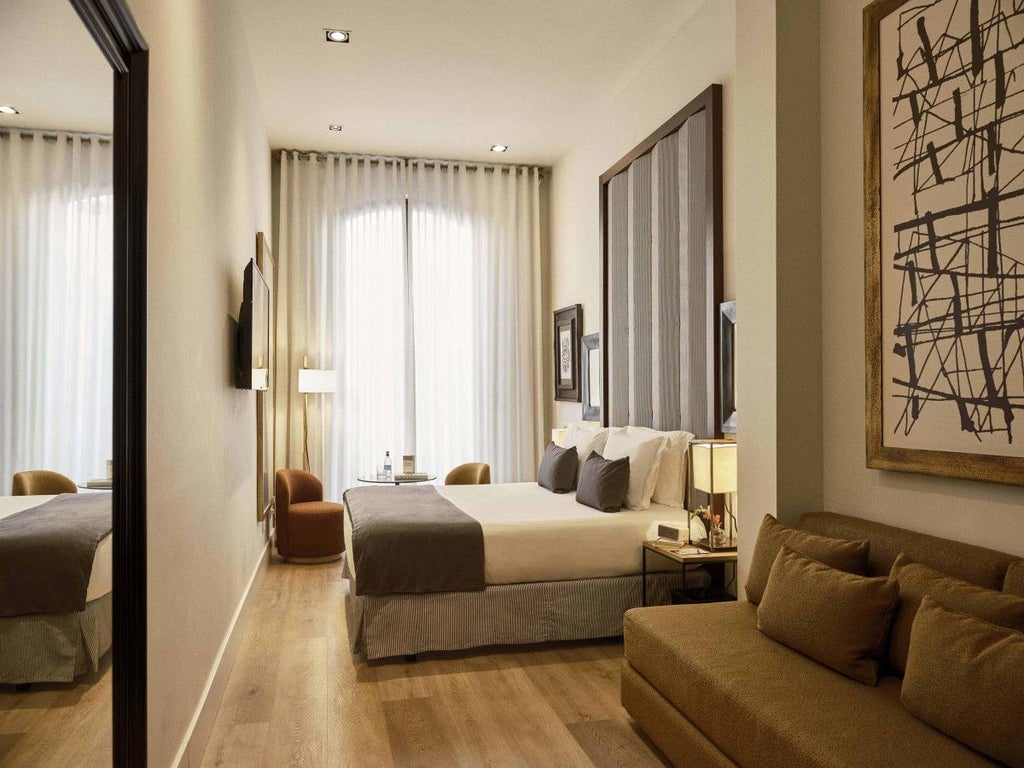 Elegant hotel room at Hotel Pulitzer Barcelona with plush white bedding, warm wood accents, and soft ambient lighting highlighting modern Spanish design