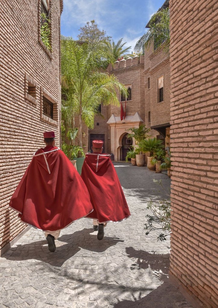 Opulent Moroccan riad hotel with ornate archways, mosaic tiles, and a tranquil courtyard pool surrounded by traditional architecture