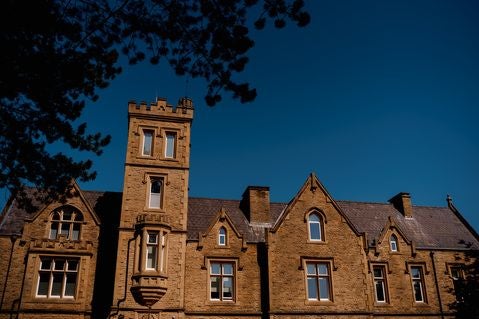 Elegant historic hotel surrounded by lush green park, featuring grand Victorian architecture with stone facade and manicured gardens at scenset.