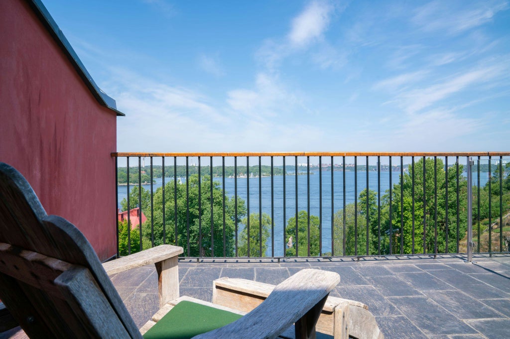 Modern, minimalist hotel room with panoramic floor-to-ceiling windows revealing sweeping sea views, featuring crisp white linens, sleek Nordic design, and soft natural light in scenic Sweden