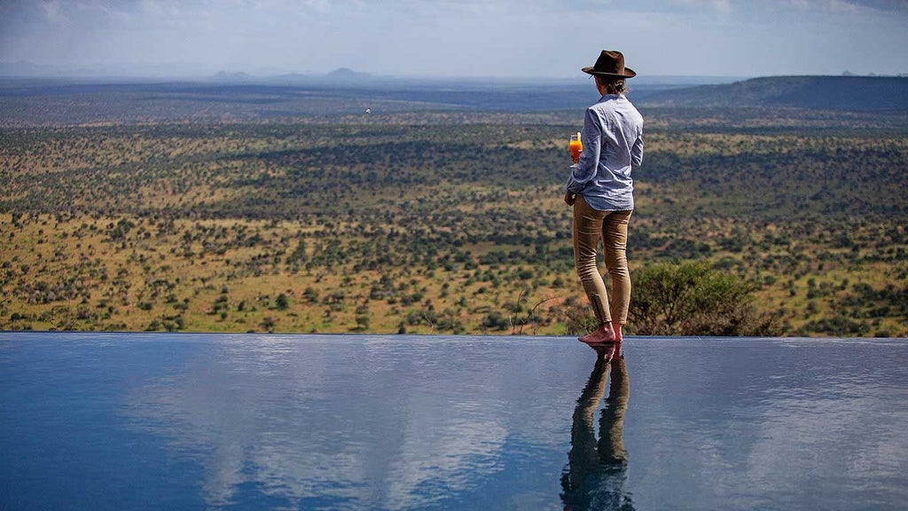 Luxurious safari tents overlooking vast Kenyan savanna landscape with distant mountains and golden grasslands at Scenset Loisaba Tented Camp