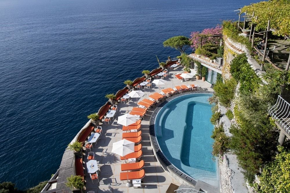 Cliffside luxury hotel in Positano with tiered terraces, elegant balconies and Mediterranean gardens overlooking the azure Amalfi Coast