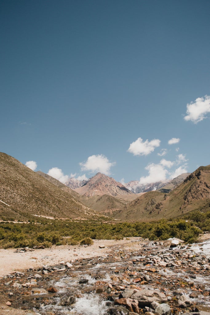 Sweeping aerial view of Mendoza's lush vineyards surrounded by snow-capped Andes mountains, showcasing opulent wine estates at sunset