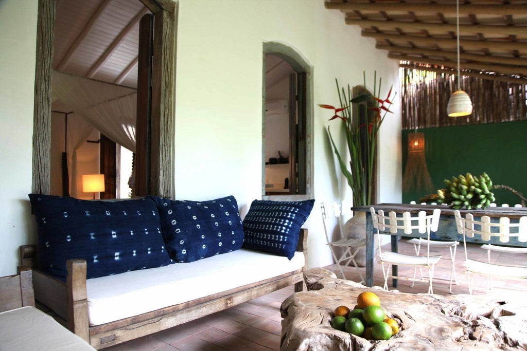 Rustic wooden bed with white linens in a luxurious Brazilian-style suite at UXUA Casa Hotel, warm sunlight filtering through traditional architectural elements