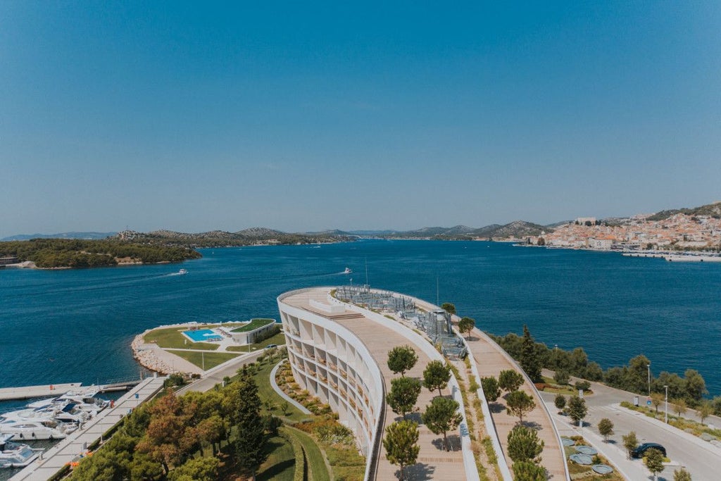 Luxurious seaside resort with modern architecture, nestled along the Adriatic coastline, featuring sleek white buildings and crystal-clear blue waters near Šibenik