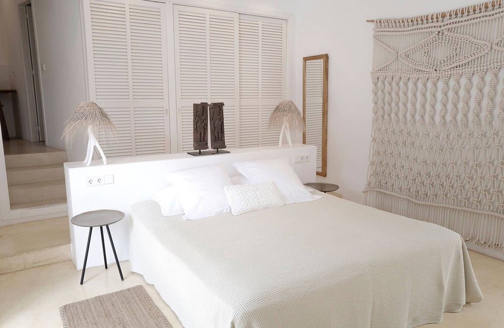 Minimalist white bedroom with clean lines, plush bedding, and large windows overlooking scenic Ibiza landscape at Pure House boutique hotel