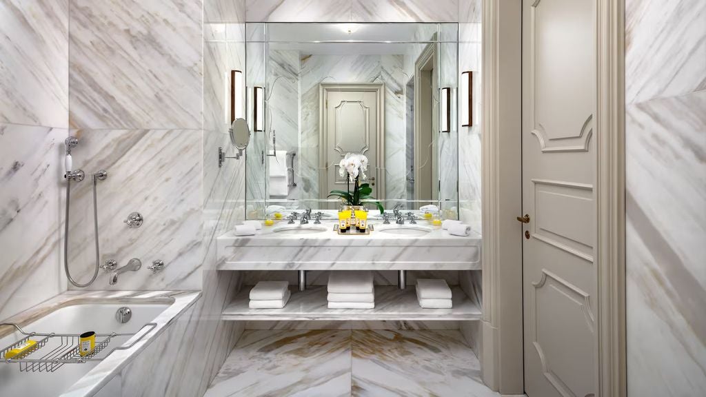 Opulent Venetian palace suite with ornate gold-framed mirrors, crystal chandelier, damask wallpaper, and antique furniture overlooking Grand Canal