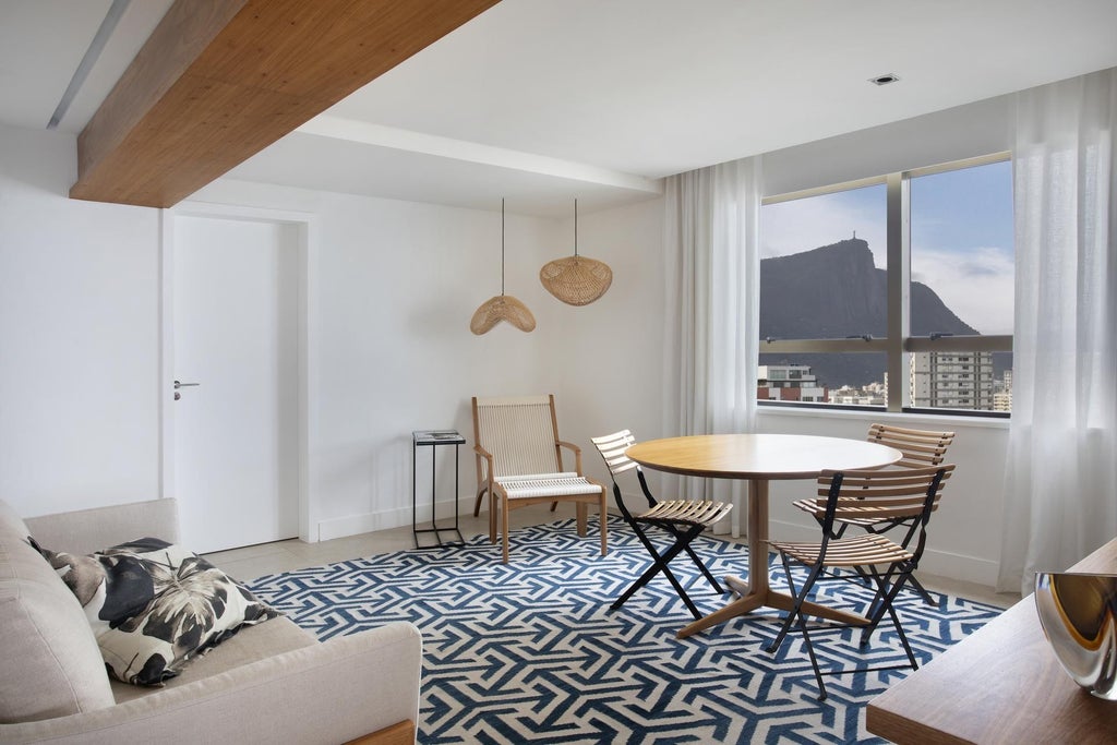 Luxurious minimalist hotel room with ocean view, neutral color palette, sleek modern furniture, and floor-to-ceiling windows overlooking Brazilian coastline