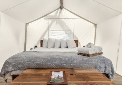 Luxurious safari-style canvas tent suite with plush king bed, rustic wooden furnishings, and panoramic views of scenic desert landscape near Zion National Park