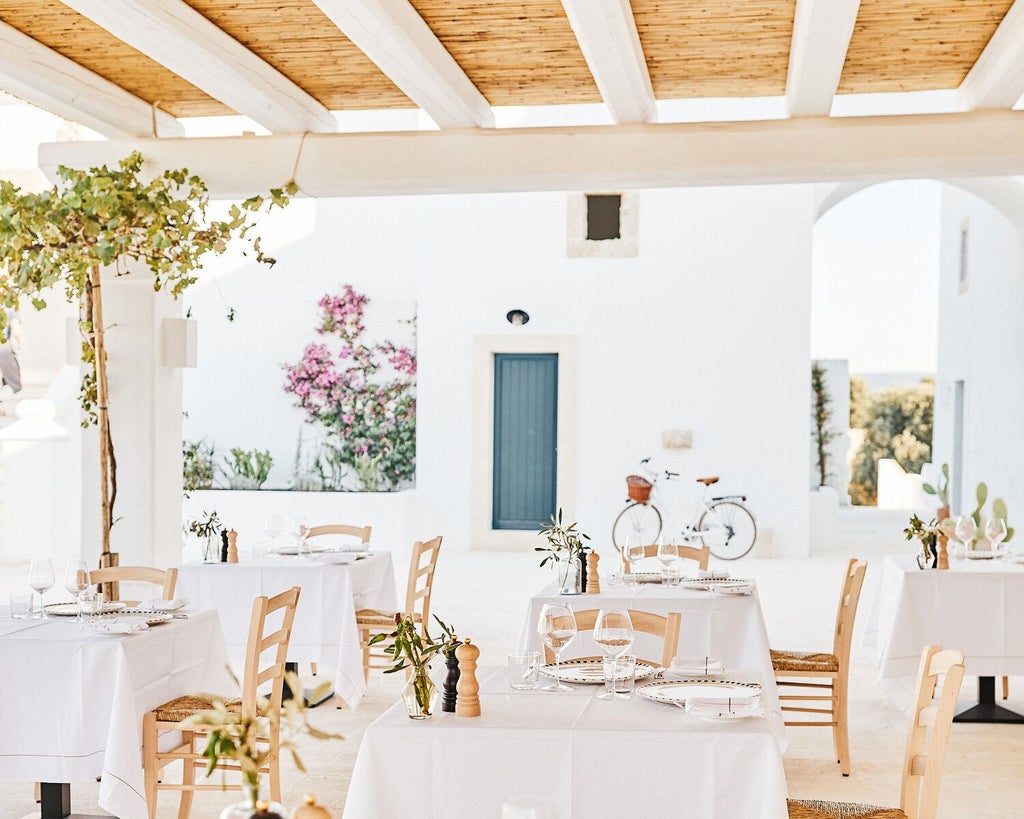 Luxurious stone farmhouse nestled in golden Puglia countryside, with rustic terracotta tiles, azure infinity pool, and lush Mediterranean landscape