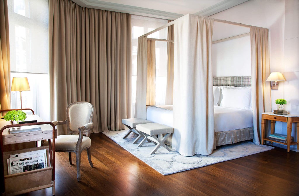 Elegant junior suite at URSO Hotel & Spa in Spain, featuring plush white bedding, modern minimalist decor, and warm neutral color palette with soft natural lighting