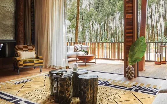 Luxurious Rwandan treehouse suite with floor-to-ceiling windows, elegant wooden decor, and panoramic forest views of Volcanoes National Park