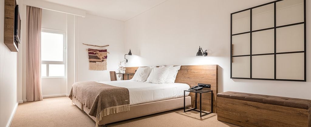 Elegant double room with garden view at Lamego Hotel, featuring plush white bedding, modern decor, and soft natural light streaming through large windows.