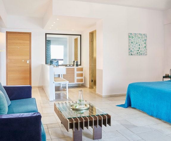 Luxurious junior suite with panoramic Aegean Sea views, elegant white decor, private balcony, and plush king-sized bed at Eagles Palace hotel in Greece.