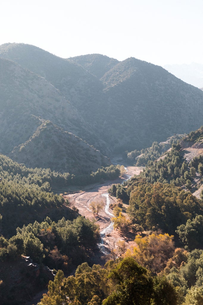 Rugged Atlas Mountains trail with sun-drenched rocky terrain, traditional Berber stone path, and expansive desert-like landscape with distant peaks