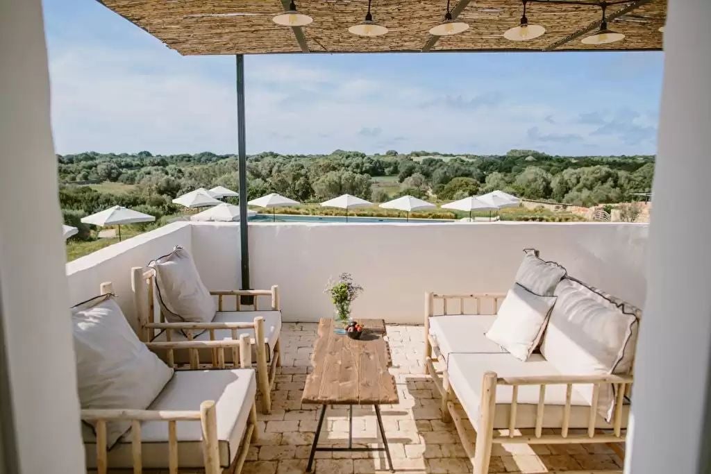 Luxurious Spanish junior suite with elegant wooden furnishings, soft neutral tones, plush bedding, and expansive windows overlooking scenic landscape at Torre Vella