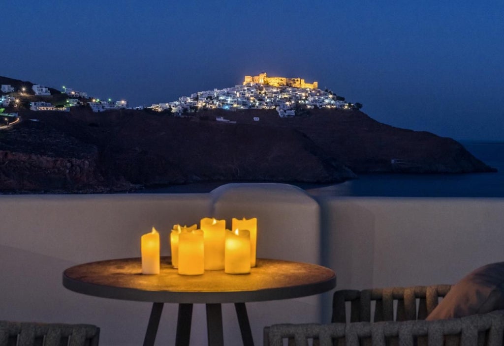 Luxurious Greek honeymoon suite with white minimalist decor, elegant four-poster bed, and stunning Aegean Sea view through large windows.