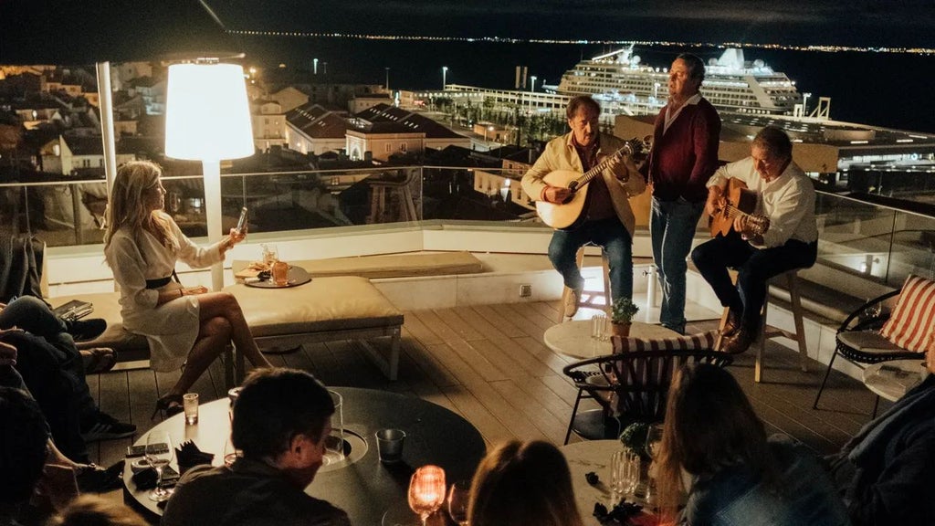 Stunning boutique hotel terrace overlooking Lisbon's historic Alfama district, with elegant white furniture and panoramic city views at sunset