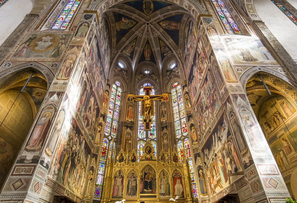 Renaissance frescoes and ornate golden artwork adorn the vaulted ceiling of the Uffizi Gallery's grand corridor in Florence, Italy