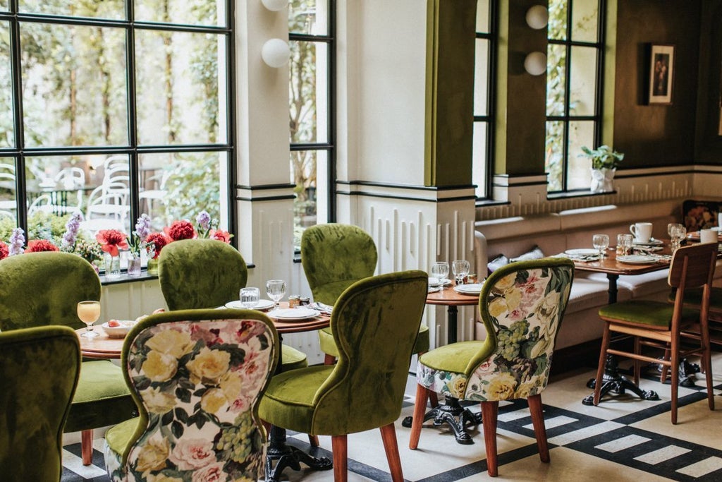 Elegant Parisian boutique hotel with soft pastel pink walls, vintage brass lamp, and plush velvet armchair in cozy, intimate lobby setting