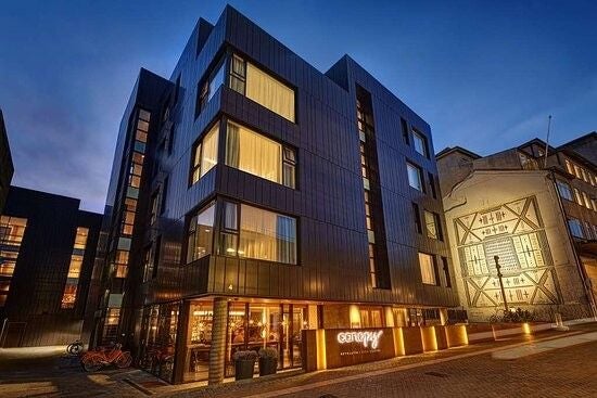 Modern Nordic-style hotel exterior with glass facade, warm lighting, snow-covered entrance, and illuminated 