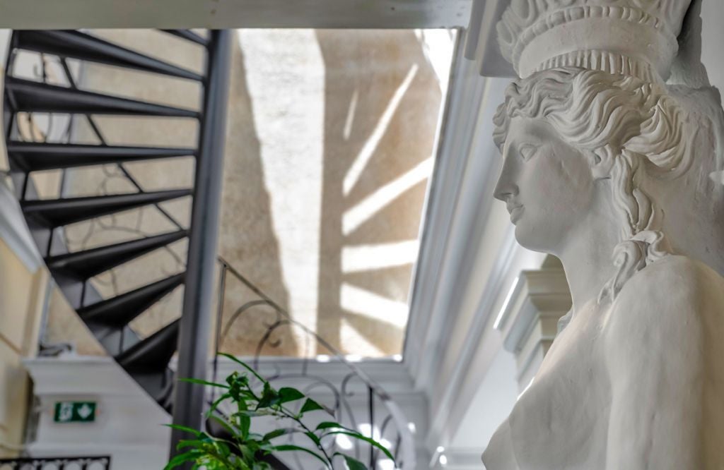 Elegant hotel facade with neoclassical architecture, featuring marble columns and ornate balconies in the heart of Athens at golden hour