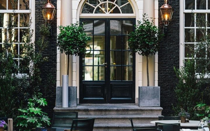 Elegant luxury hotel entrance with classic Dutch architecture, featuring wrought iron gates and decorative stone facade in Amsterdam