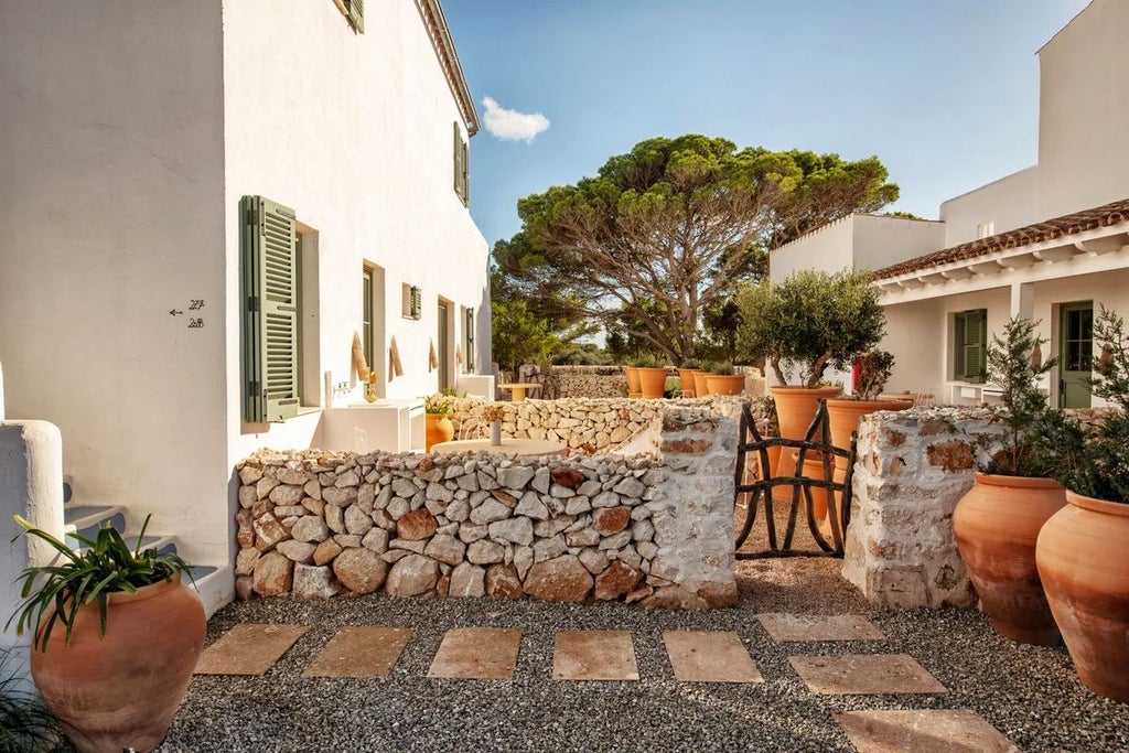 Luxurious whitewashed Spanish villa with blue accents, surrounded by lush Mediterranean greenery and sun-drenched stone terrace overlooking coastal landscape.