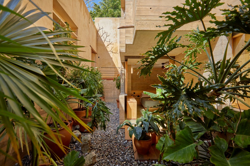 Luxurious boutique hotel nestled in Oaxaca's landscape, featuring minimalist design, stone walls, and a serene infinity pool overlooking lush greenery.