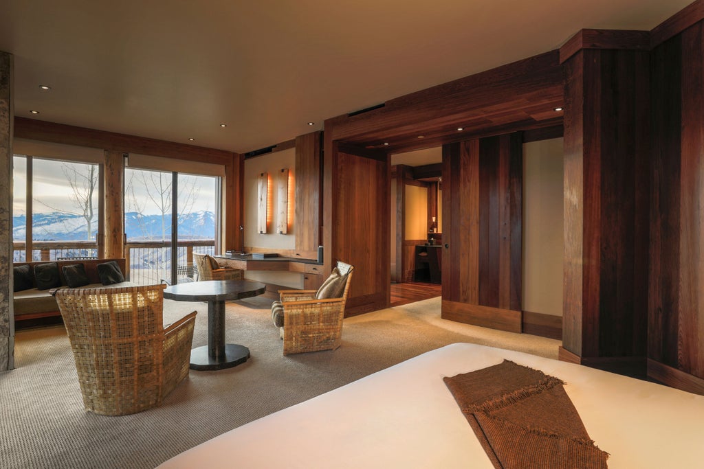 Luxurious mountain resort with infinity pool overlooking snow-capped Grand Tetons, surrounded by rugged Wyoming wilderness