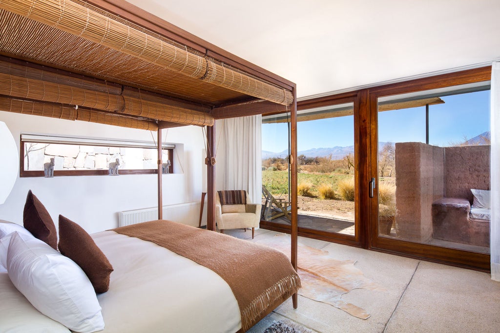 Modern desert resort with glass walls and wooden terraces overlooking Licancabur volcano across stark Atacama Desert landscape