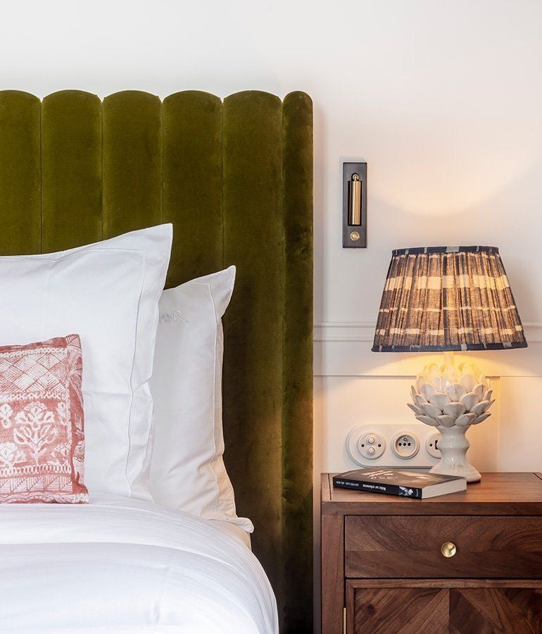 Elegant French-inspired hotel room with Asian influences, featuring plush bedding, rich wood furnishings, and soft ambient lighting in neutral tones