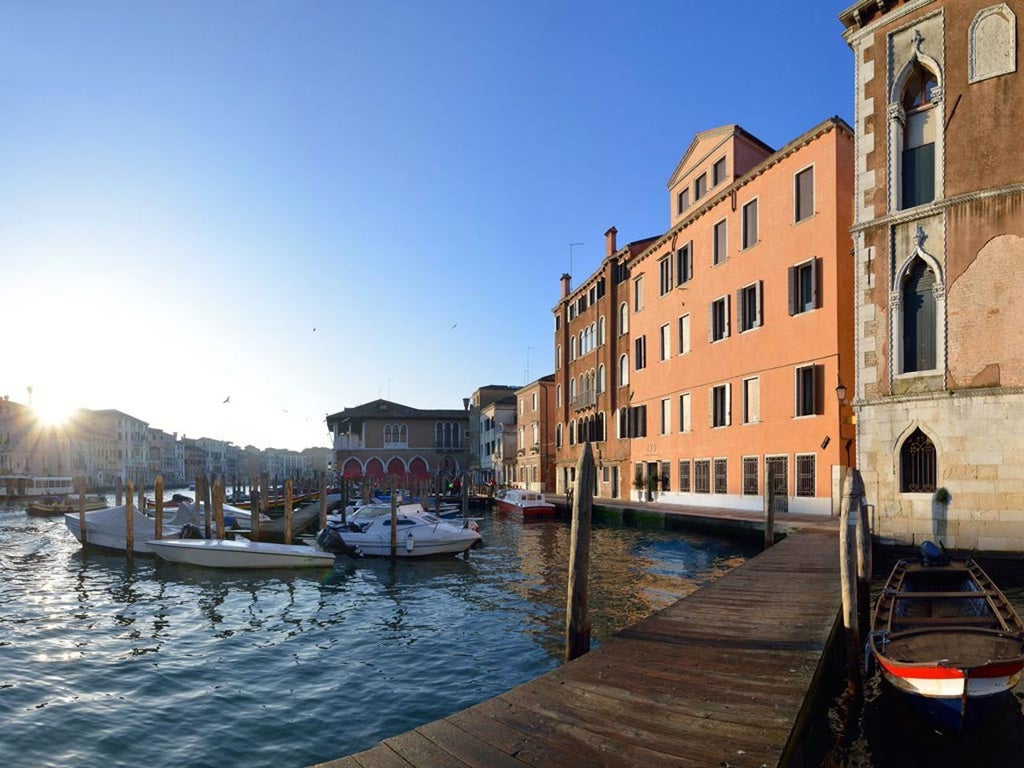 Elegant boutique hotel facade featuring vintage-style clock design, red brick walls, and ornate windows in Florence's historic center