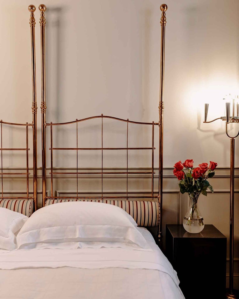 Elegant Italian hotel room with plush white bedding, vintage hardwood floors, and soft neutral tones creating a serene, luxurious Classic accommodation space