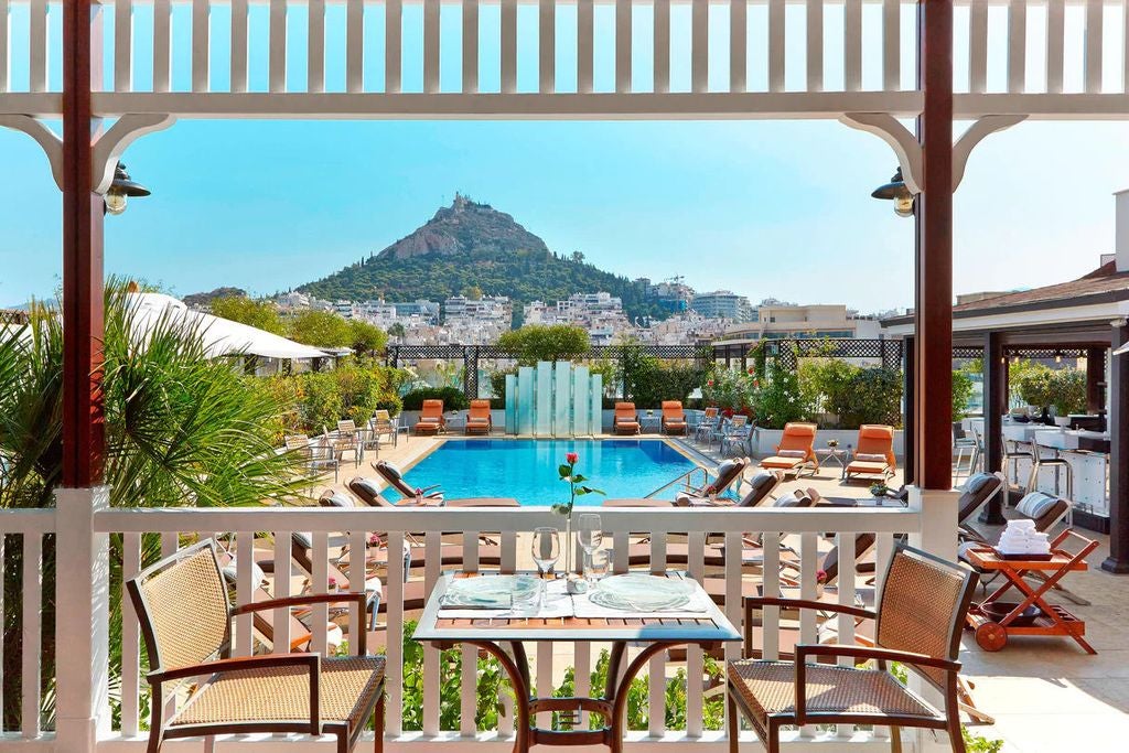 Hotel Grande Bretagne's neoclassical facade with ornate columns, grand balconies, and elegant lighting against Athens' evening skyline