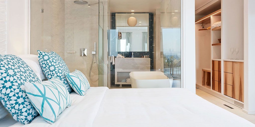 Luxurious Thalassa Suite at Myconian Ambassador Hotel with panoramic Aegean Sea view, white minimalist decor, and private infinity pool overlooking scenic Greek coastline