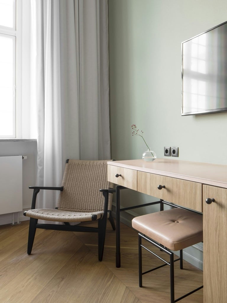 Elegant superior hotel room with minimalist Nordic design, soft neutral color palette, modern furniture, and warm ambient lighting in Copenhagen