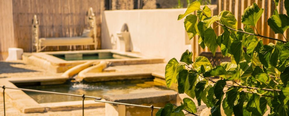 Luxurious Mediterranean hotel with traditional stone facade, nestled in scenic Italian landscape, featuring elegant balconies and warm evening lighting