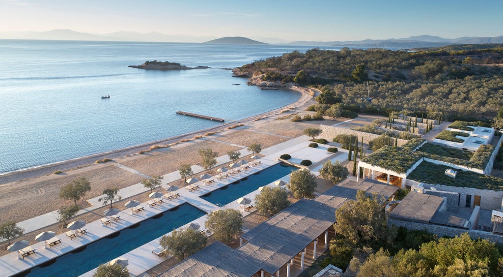 Luxurious Greek resort with white stone pavilions, infinity pools, and endless ocean views nestled in olive-studded hills at sunset