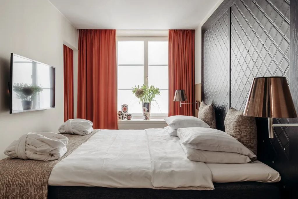 Elegant junior suite at scenset Hotel with plush white bedding, modern minimalist decor, soft neutral tones, and expansive city view through large windows