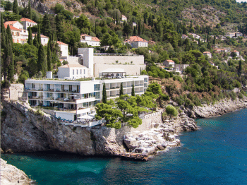 Modern luxury hotel built into cliffside overlooking Adriatic Sea, featuring white stone terraces and infinity pool with panoramic views