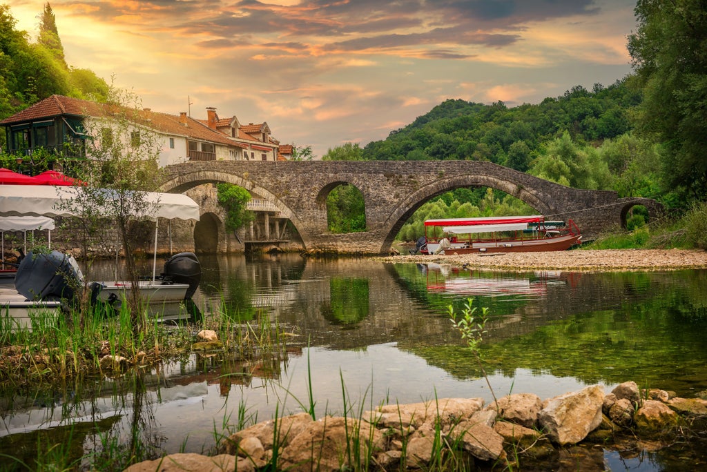 Rugged mountain peaks of Montenegro rise dramatically against a golden sunset, showcasing luxury hiking trail with pristine alpine landscape and turquoise valley below.