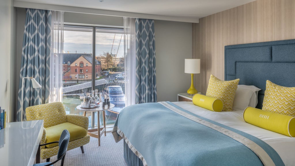 Elegant standard double hotel room with modern decor, soft neutral tones, plush bedding, and contemporary furnishings overlooking urban landscape