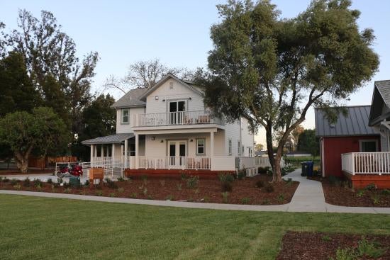 Elegant two-story white boutique hotel with colonial-style pillars, surrounded by lush greenery and featuring french windows at sunset