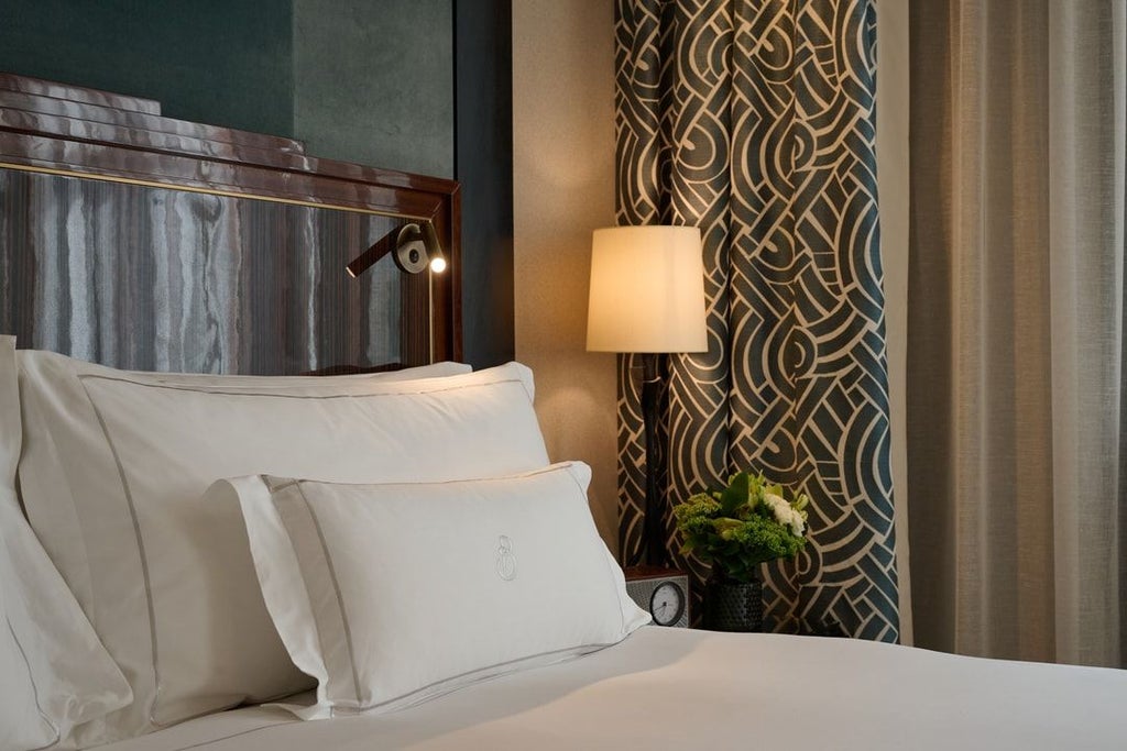 Elegant classic hotel room with soft neutral tones, plush king bed, luxurious white linens, and refined Art Deco-inspired furnishings in Mayfair, London