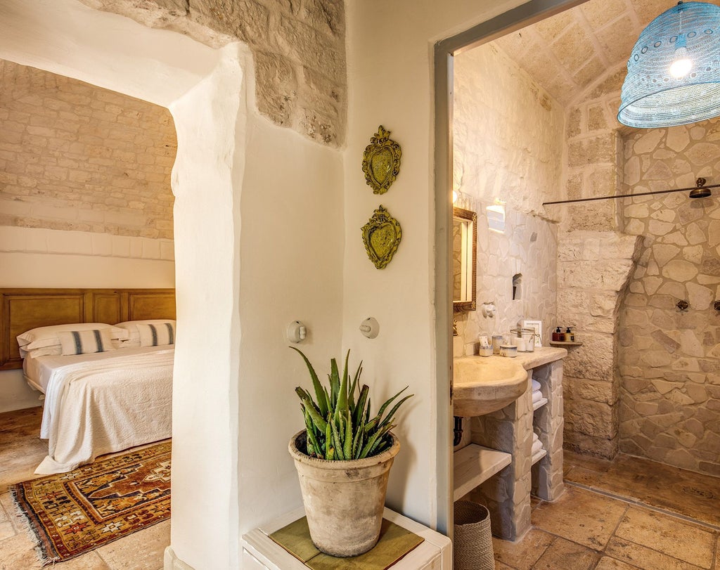 Elegant stone-walled superior room at Masseria Cervarolo with rustic white-draped bed, traditional Italian countryside decor, and warm natural lighting