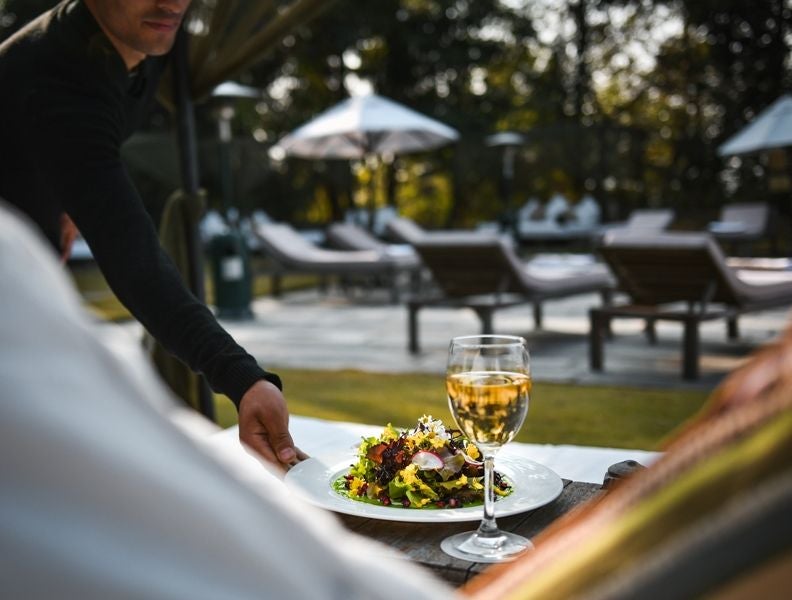 Traditional Nepali luxury resort with ornate wooden architecture nestled in mountains, featuring terraced stone buildings and panoramic views