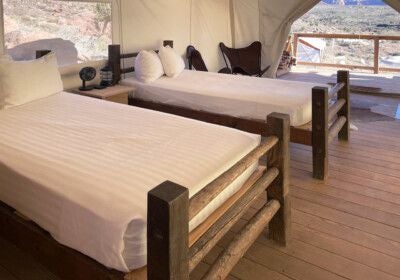 Luxurious safari-style canvas tent suite with king bed, rustic wooden furniture, and panoramic mountain views of Zion National Park landscape